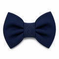A navy blue bow tie with a debossed dog logo on a white background