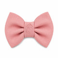 A pink bow tie with a debossed dog design on a white background