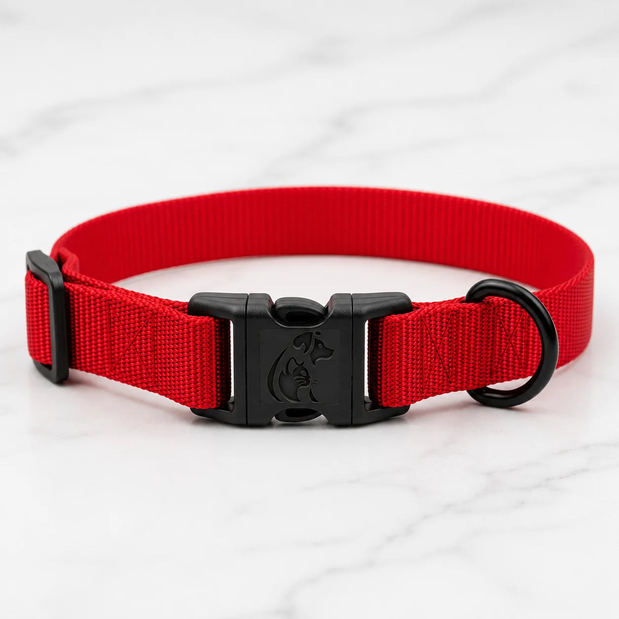 A bright red nylon dog collar with black plastic buckle and hardware on marble