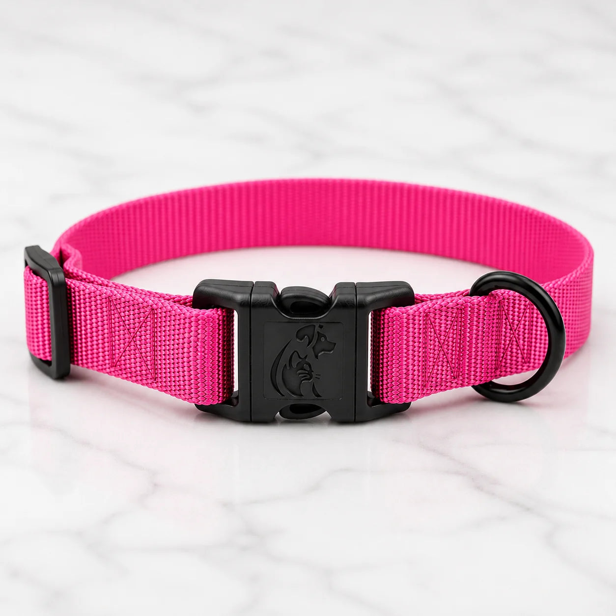 A vibrant pink dog collar with a black buckle and hardware on a marble surface