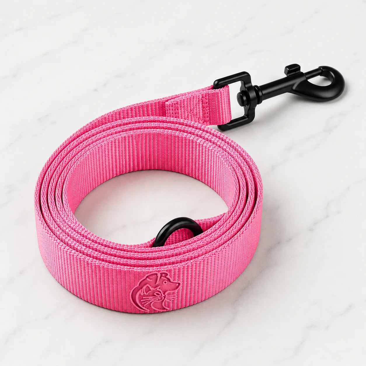 A pink dog leash with a black clip on a white marble surface