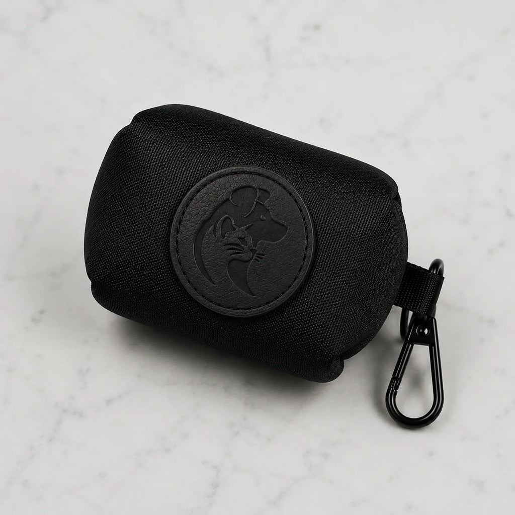 Black dog poop bag holder with metal clip and embossed dog logo on white marble background