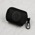 Black dog poop bag holder with metal clip and embossed dog logo on white marble background