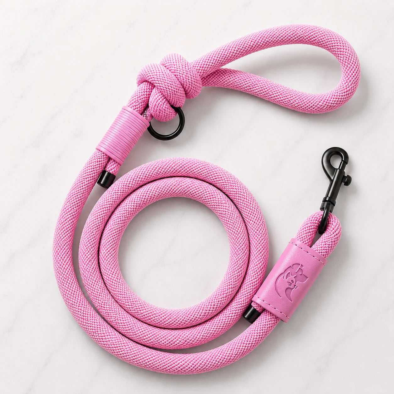 Pink dog leash with coiled rope and leather handle on white marble background