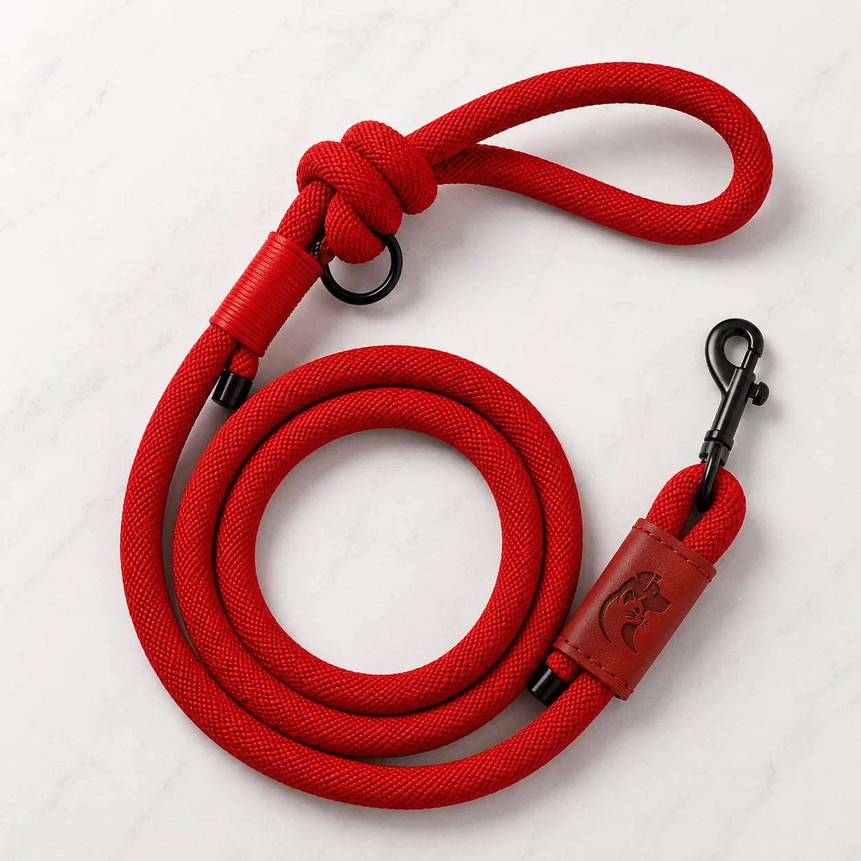 Red rope dog leash with leather accents and metal clips on white background