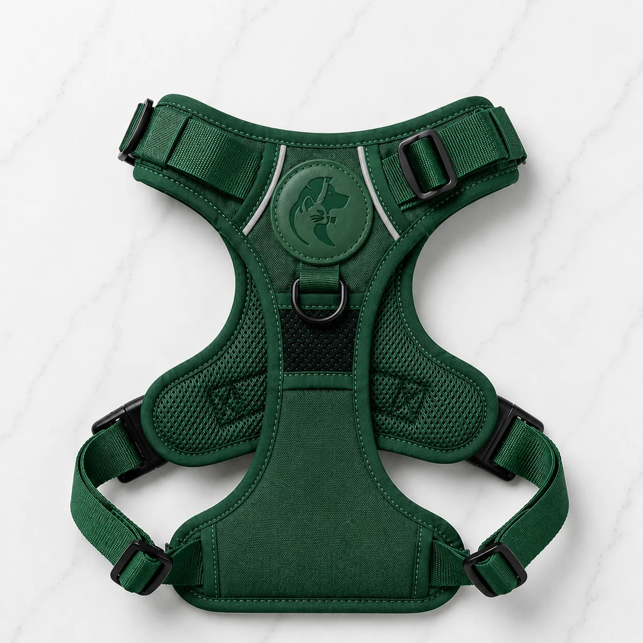 Green dog harness with black buckles and logo on white marble background